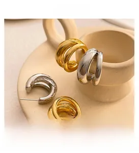 Detail of overlapping C-shaped hoop earrings in gold and silver finish on ceramic tray