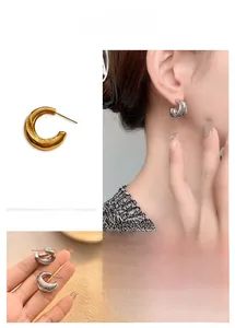 Detail of twisted double layer C-shaped earrings in gold and silver finish