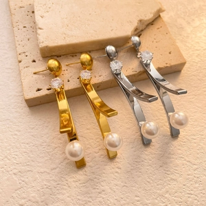 Dettaglio di orecchini pendenti in oro e argento con zirconi geometrici e perle su pietra