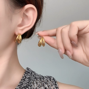 Close-up of double-layered C-shape gold earrings with brushed matte texture on model