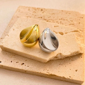 Makro-Detail von Tropfenohrringen in Gold und Silber auf Travertin-Steinplatten