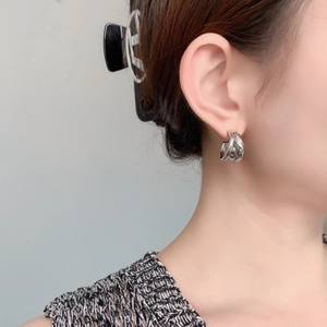 Detail of silver double-layered C-shape earrings with zircon inlay on model