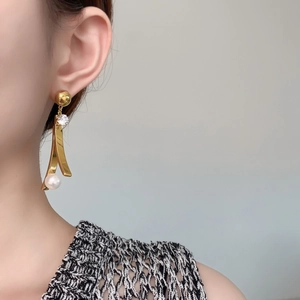 Dettaglio di eleganti orecchini a goccia placcati oro con zircone e perla su modella