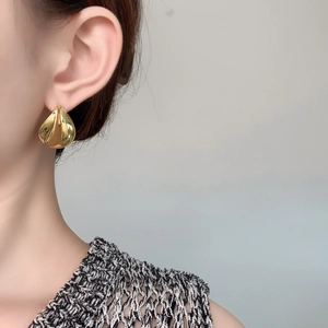 Detail von eleganten vergoldeten Tropfenohrringen am Model mit Hochglanzoberfläche