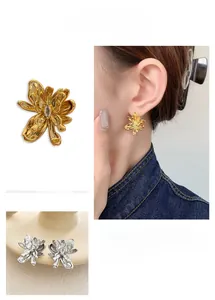 Detail view of 18K gold plated flower earrings with droplet zircon and liquid metal texture
