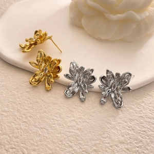 Detailed view of gold and silver flower stud earrings with zircon on a white plate