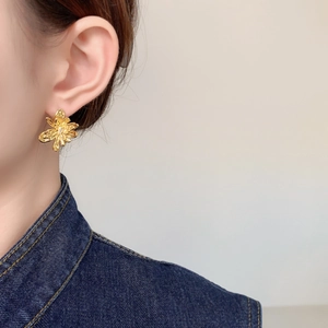 Close-up of minimalist 18K gold plated flower stud earring worn by a model