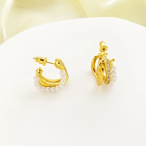 Detailed view of gold-plated C-shaped earrings with rows of white pearls and cubic zirconia