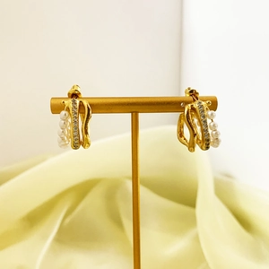 Detail of gold layered hoop earrings with cubic zirconia and pearls on T-bar stand