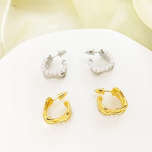 Detail of C-shaped hoop earrings with pearls and irregular gold texture on silk backdrop