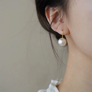 Elegant white pearl earring with gold hook shown on ear for a minimalist jewelry look