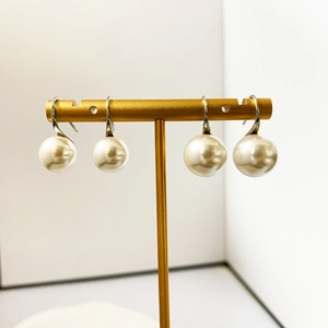 Detail of elegant white pearl drop earrings on a gold stand with soft iridescent luster