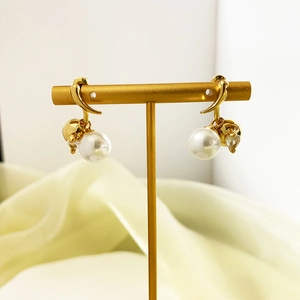 Detailed view of elegant pearl drop earrings with 18K gold plating on a silk background