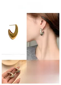 Detailed view of hollow hook-shaped gold and silver earrings in a polished metallic finish