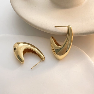 Detail of 18k gold plated chunky V-shaped hoop earrings on elegant ceramic display