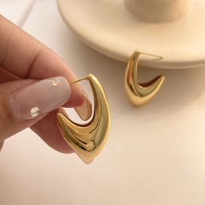 Detail of 18k gold plated hollow hook earrings with glossy finish and modern design
