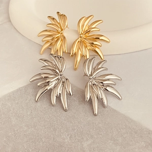 Modern angel wing stud earrings in gold and silver finishes on a marble surface