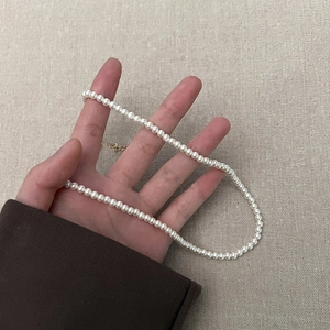 Close-up van elegante parelketting met gouden sluiting tegen een getextureerde achtergrond
