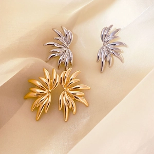 Elegant gold and silver angel wing stud earrings displayed on premium champagne silk fabric