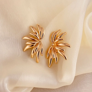 Modern gold-plated angel wing earrings with a radiant streamlined design on silk fabric