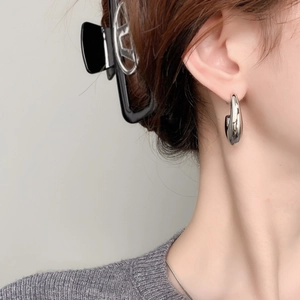 Detail view of minimal C-shaped silver hook earrings with a high-polished mirror finish