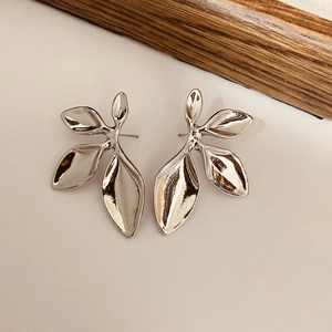 Detailed view of polished silver leaf earrings with abstract flowing metallic texture