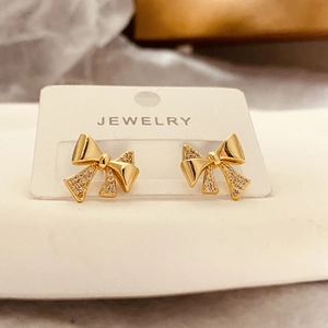 Detail of gold bow earrings featuring cubic zirconia paving on white jewelry card