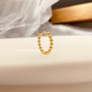 Boucles d'oreilles créoles dorées avec texture perlée sur un support blanc épuré