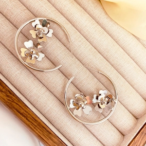 Gros plan de créoles argentées avec fleurs 3D sur un coffret à bijoux en velours texturé