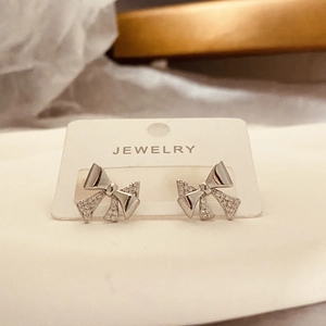 Macro shot of silver bow stud earrings with micro-pave crystals on a jewelry card