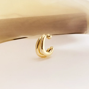 Macro shot of double-layered gold C-shape hoop earrings with polished metallic texture