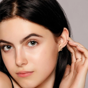 Gros plan de boucles d'oreilles créoles dorées au design perlé portées par un mannequin