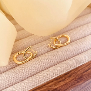 Dettaglio ravvicinato di orecchini a cuore intrecciati placcati oro a forma di U