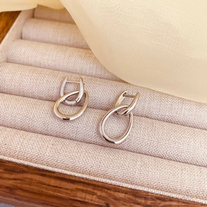 Dettaglio di orecchini a doppio cerchio a forma di U in argento su base beige