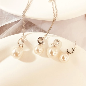 Parure élégante avec colliers en perles blanches et boucles d'oreilles sur un plateau