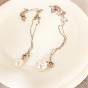 Collier élégant avec pendentif perle blanche et chaîne en acier inoxydable sur assiette
