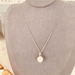 Détail d'un pendentif perle blanche unique sur une chaîne en acier inoxydable argenté