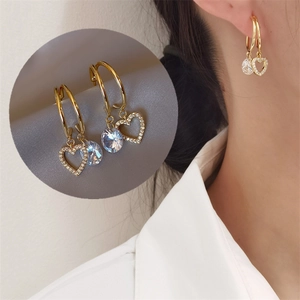 Detail of gold double-hoop earrings featuring pavé heart and large round cubic zirconia