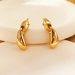 Detailed view of polished gold water drop earrings on a minimalist white display tray