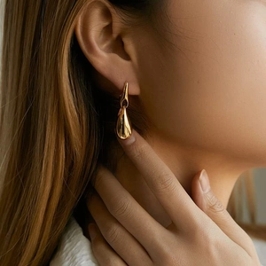 Elegant gold teardrop earrings with high-polish finish on a model for a luxury style