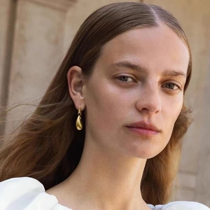 Close-up of model wearing polished gold teardrop earrings with a minimalist sleek design
