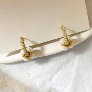 Vue détaillée des boucles d'oreilles dorées avec pavé de zircons et accents de perles