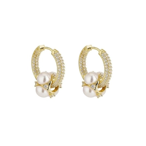 Détail de boucles d'oreilles créoles dorées avec pavé de cristaux et trois perles