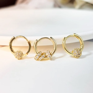 Macro detail of gold plated earrings featuring sparkling cubic zirconia and drop charms