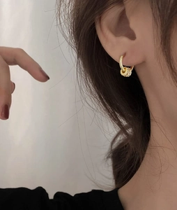 Close-up of elegant gold huggie earrings with cubic zirconia charms worn by model