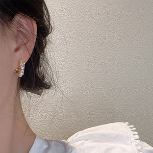 Elegant C-shaped silver earrings featuring zircon baguette stones on a female model