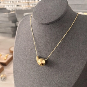 Collier avec pendentif goutte en or poli présenté sur un buste à bijoux