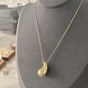 Vue détaillée du pendentif goutte d'eau plaqué or avec texture martelée sur une chaîne fine