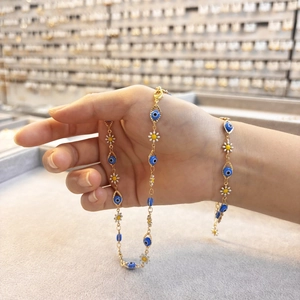 Detail der 14K vergoldeten Kette mit Evil-Eye-Anhängern und Gänseblümchen-Emaille-Elementen