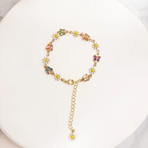 Detail von 14K vergoldetem Armband mit bunten Emaille-Schmetterlingen und Gänseblümchen